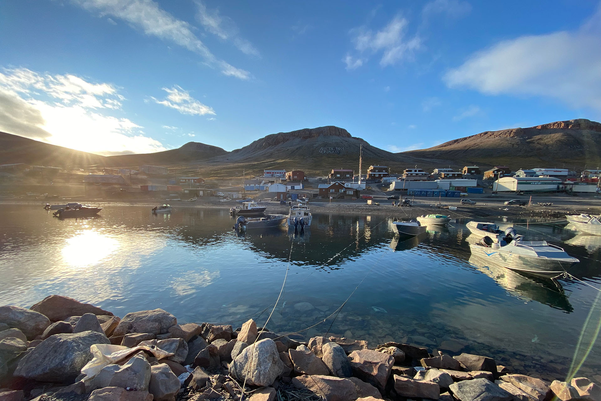A harbour at Arctic Bay, Nunavut, with small boats at anchor beneath the midnight sun.
