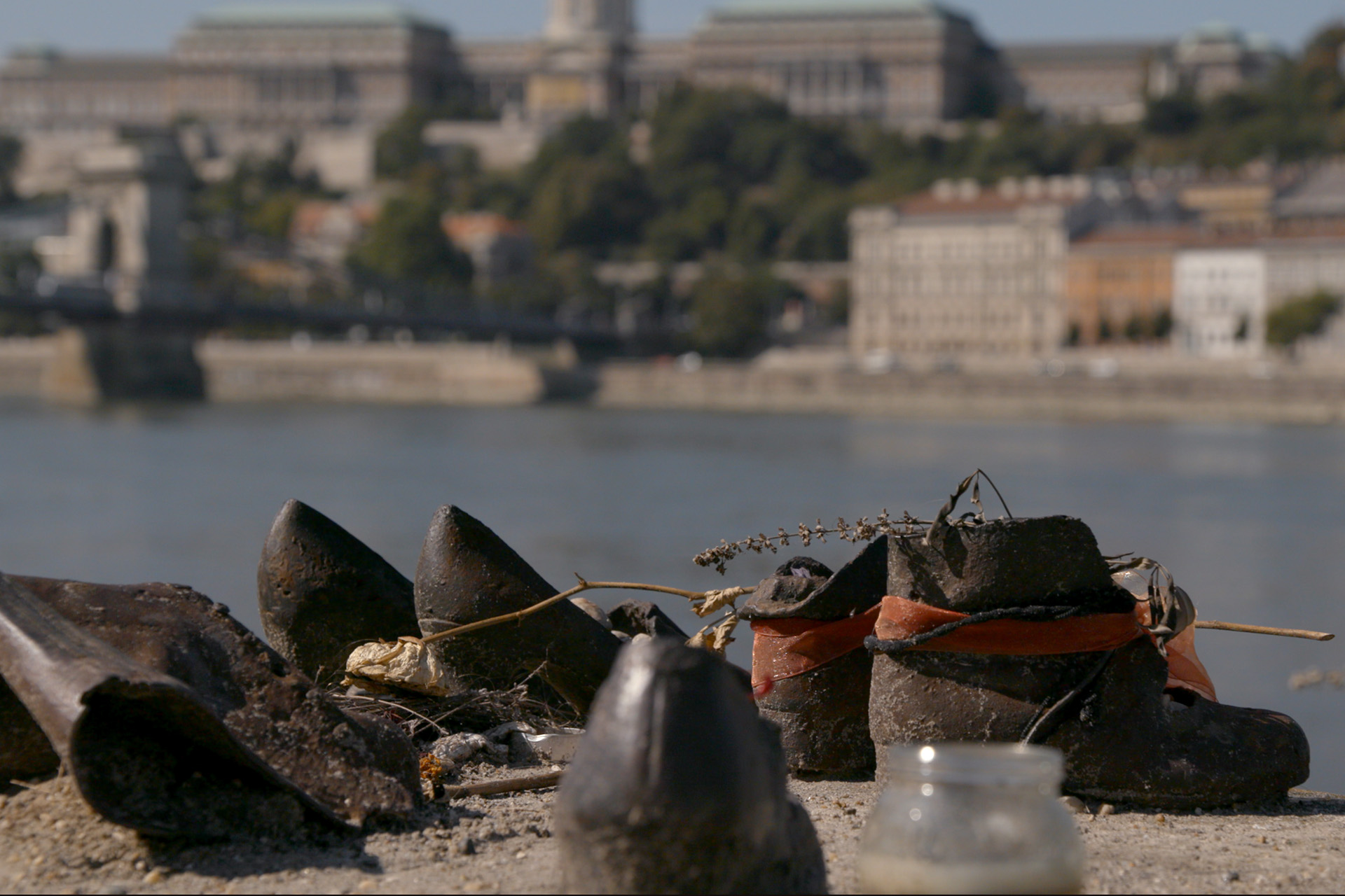 The Shoes on the Danube Bank memorial in Budapest, cast iron shoes along the riverbank with the Buda Castle skyline in the background.